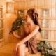 Young woman relaxing in a sauna dressed in a towel. Interior of new Finnish sauna, infrared panels for medical procedures, classic wooden sauna