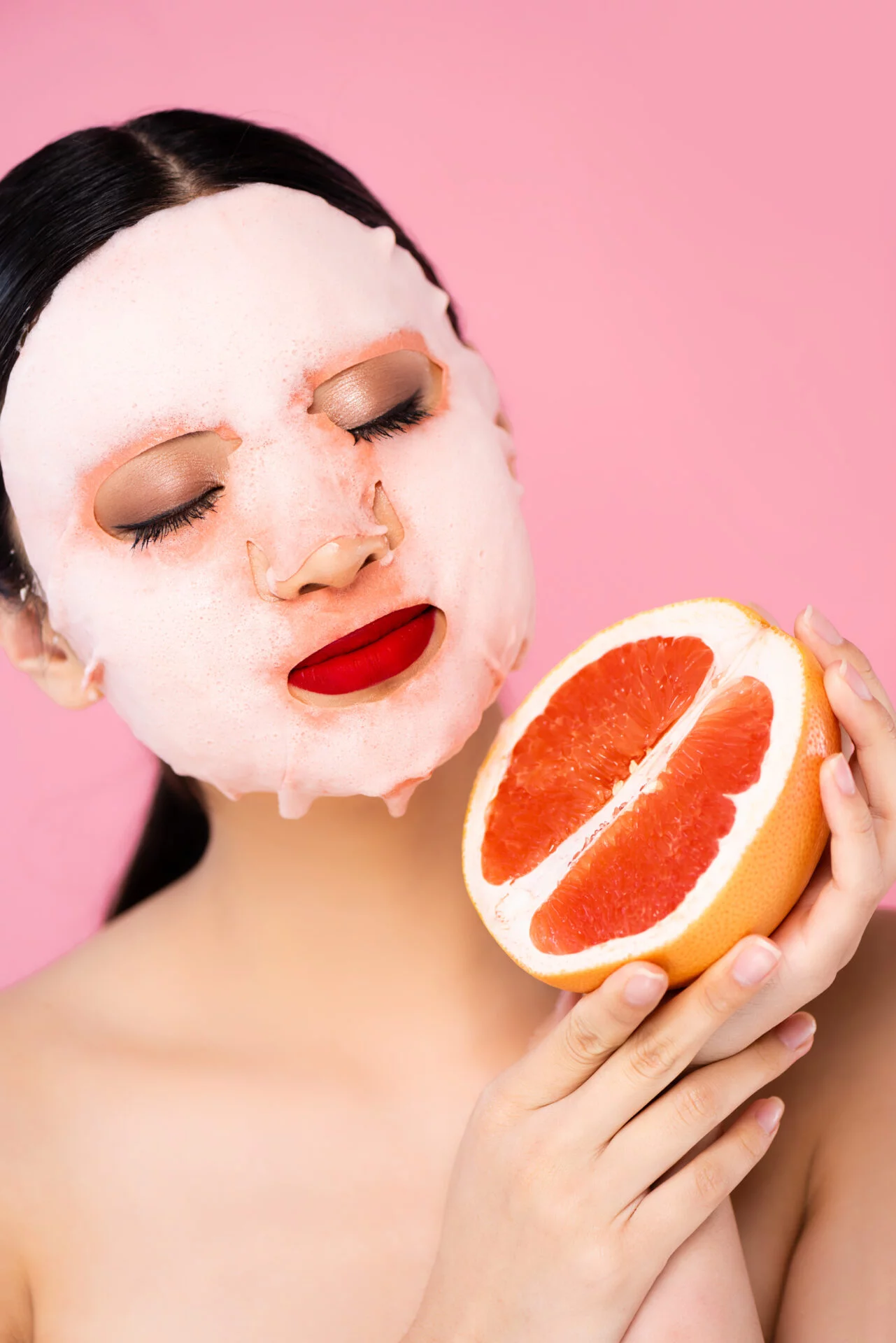 Korean woman with a non-toxic k-beauty face mask holding a grapefruit