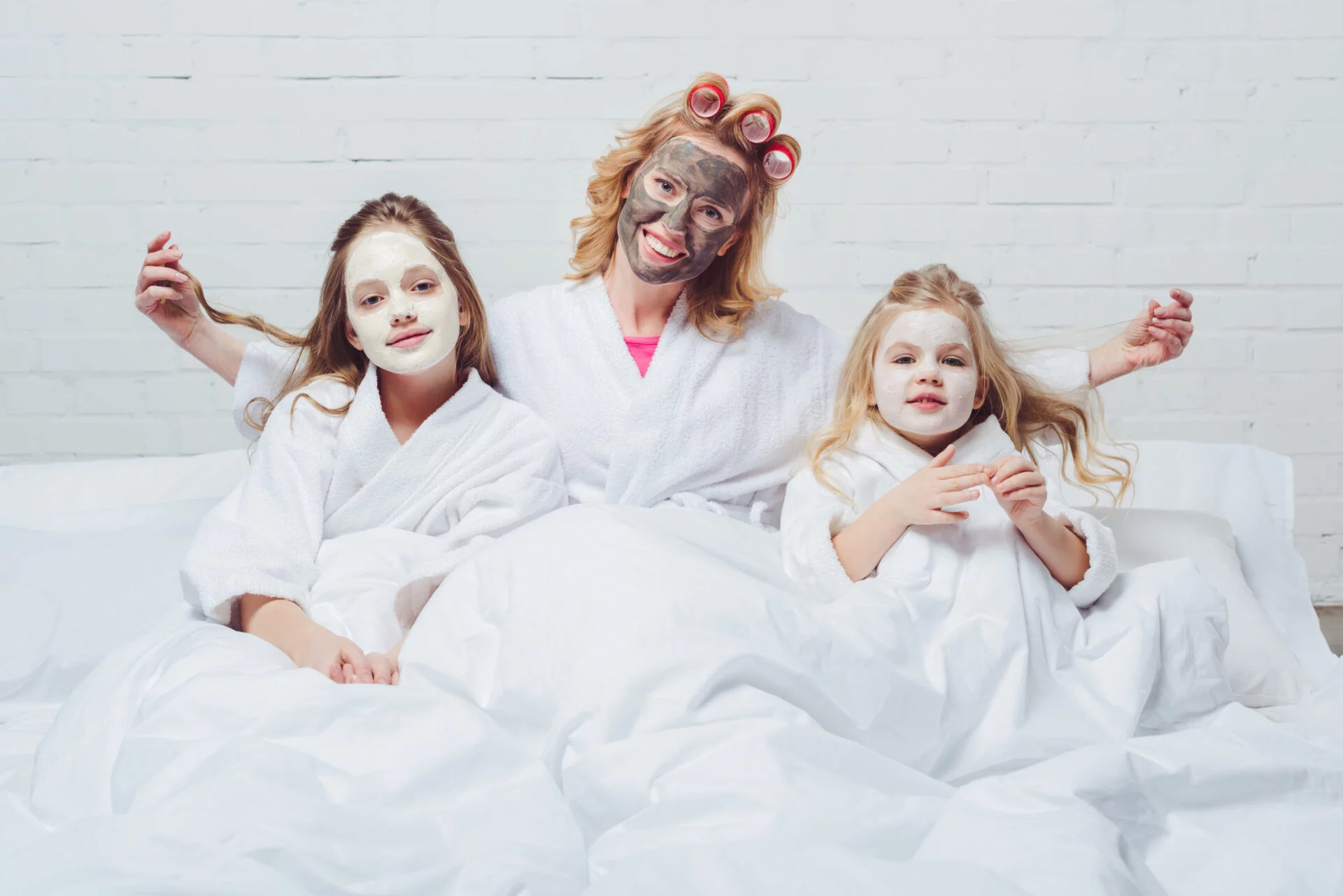 Mother with two daughters having a peel-off face mask slumber party