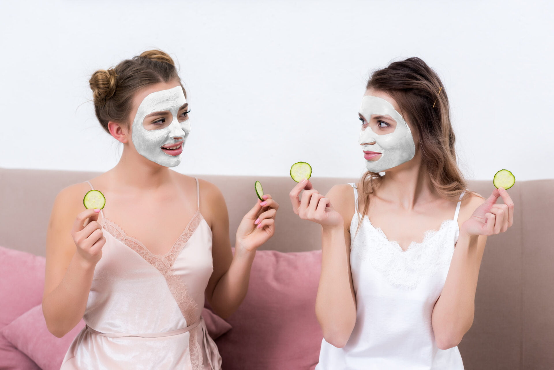 Women sitting together with pull off face masks and cucumbers for their eyes