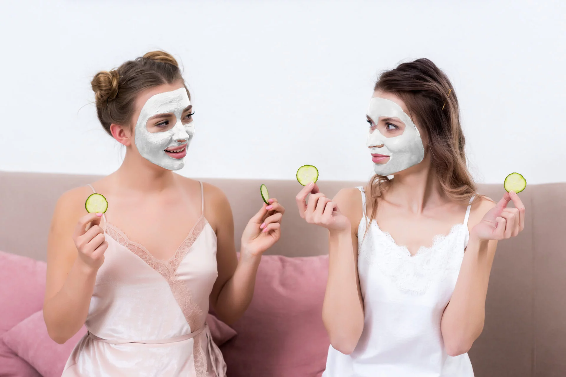 Women sitting together with pull off face masks and cucumbers for their eyes