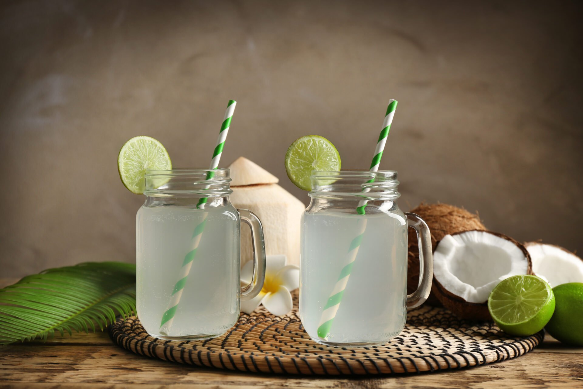 Two mason jars with coconut water on straw mat