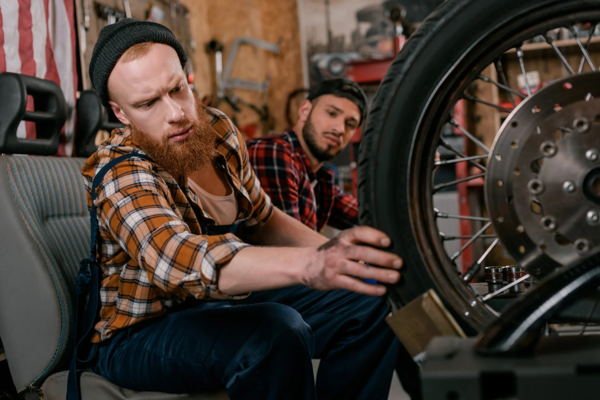 Handsome redheaded man fixing a bike in the shop