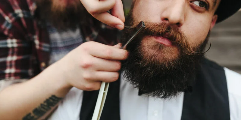 barber shaves a bearded man in vintage atmosphere