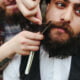 barber shaves a bearded man in vintage atmosphere