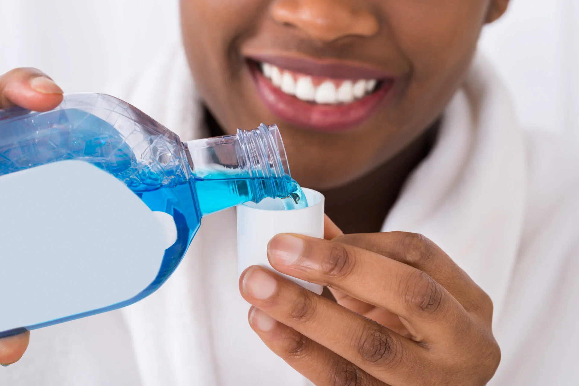 Close-up Of A Smiling Woman Pouring Mouthwash Into Cap