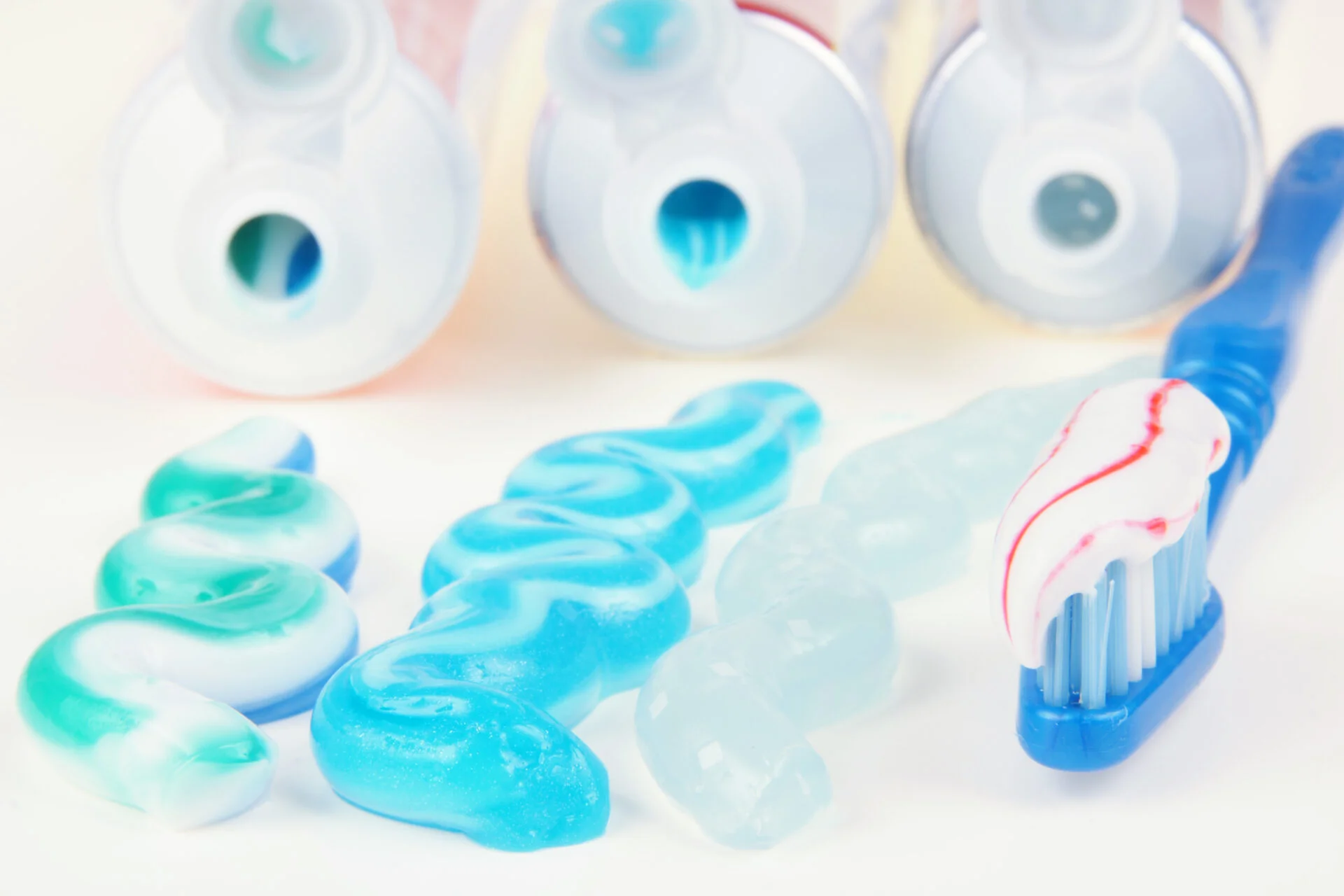 Three types of toothpaste in tubes with toothbrush