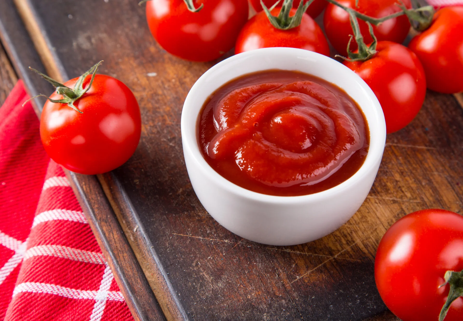 Bowl of tomato sauce and cherry tomatoes on wooden table, close-up.