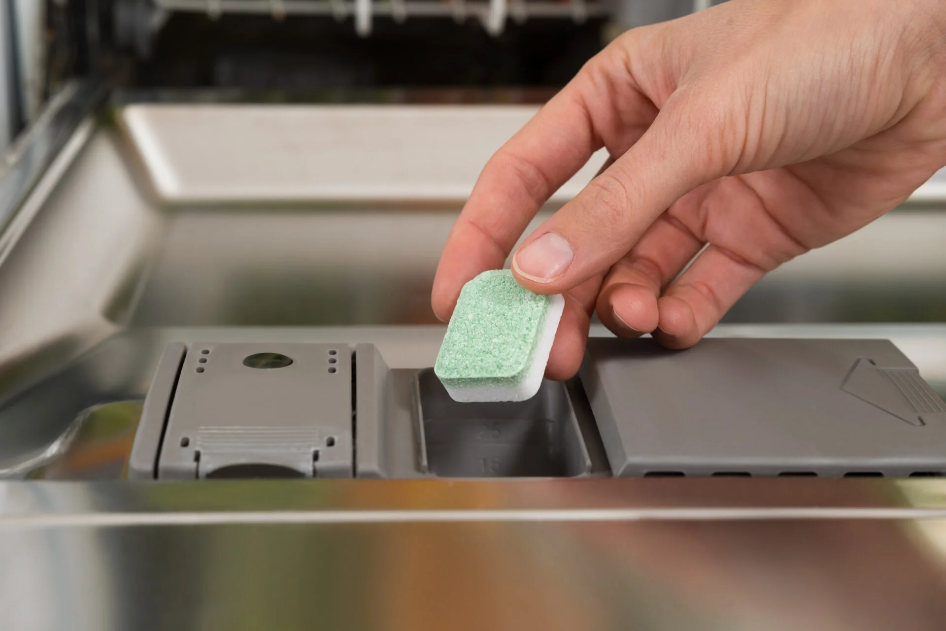 Close-up Of Person Hands Putting Dishwasher Soap Tablet In Detergent Dishwasher Box