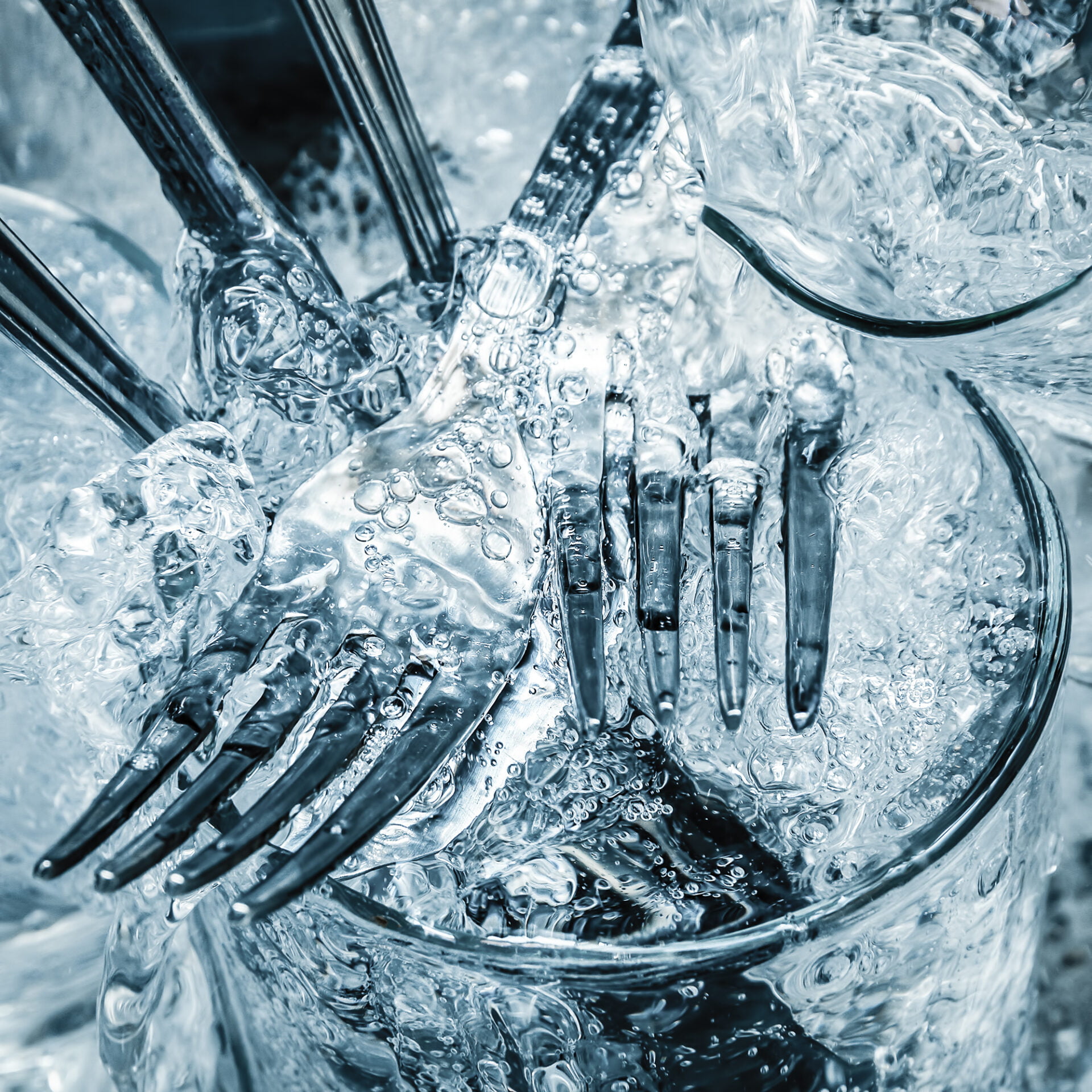 Forks,knives and glasses under a stream of water