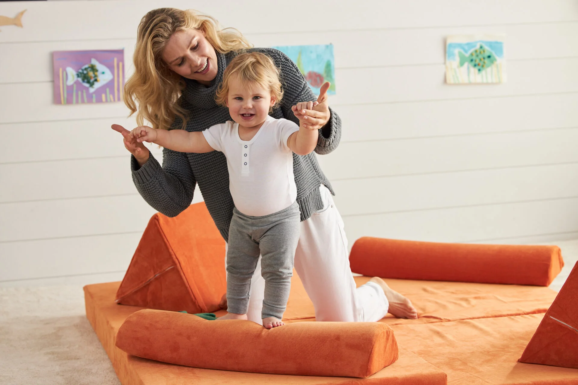 child playing on nugget styled play couch with mother