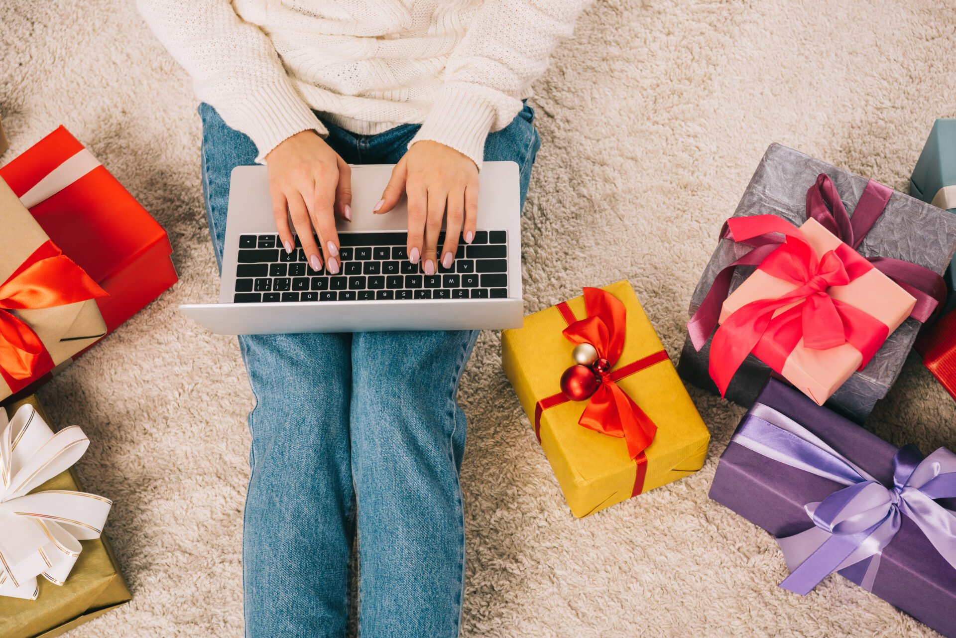 woman on her computer in front of holiday gifts