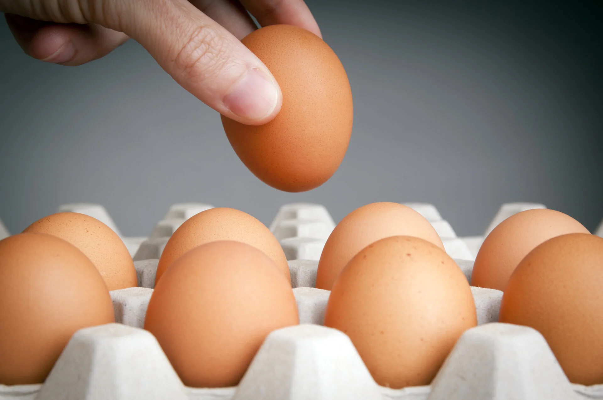 Person choosing the best egg from a carton of eggs