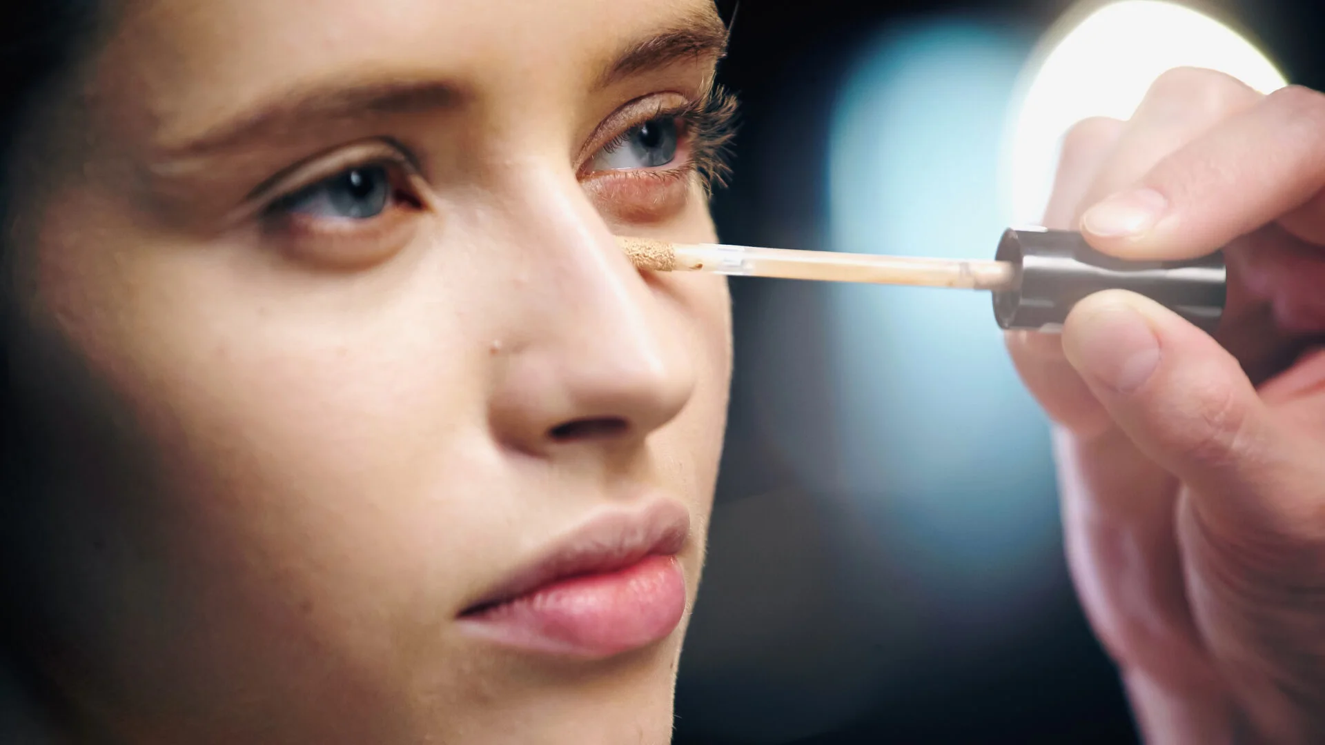 woman putting foundation on her eyes