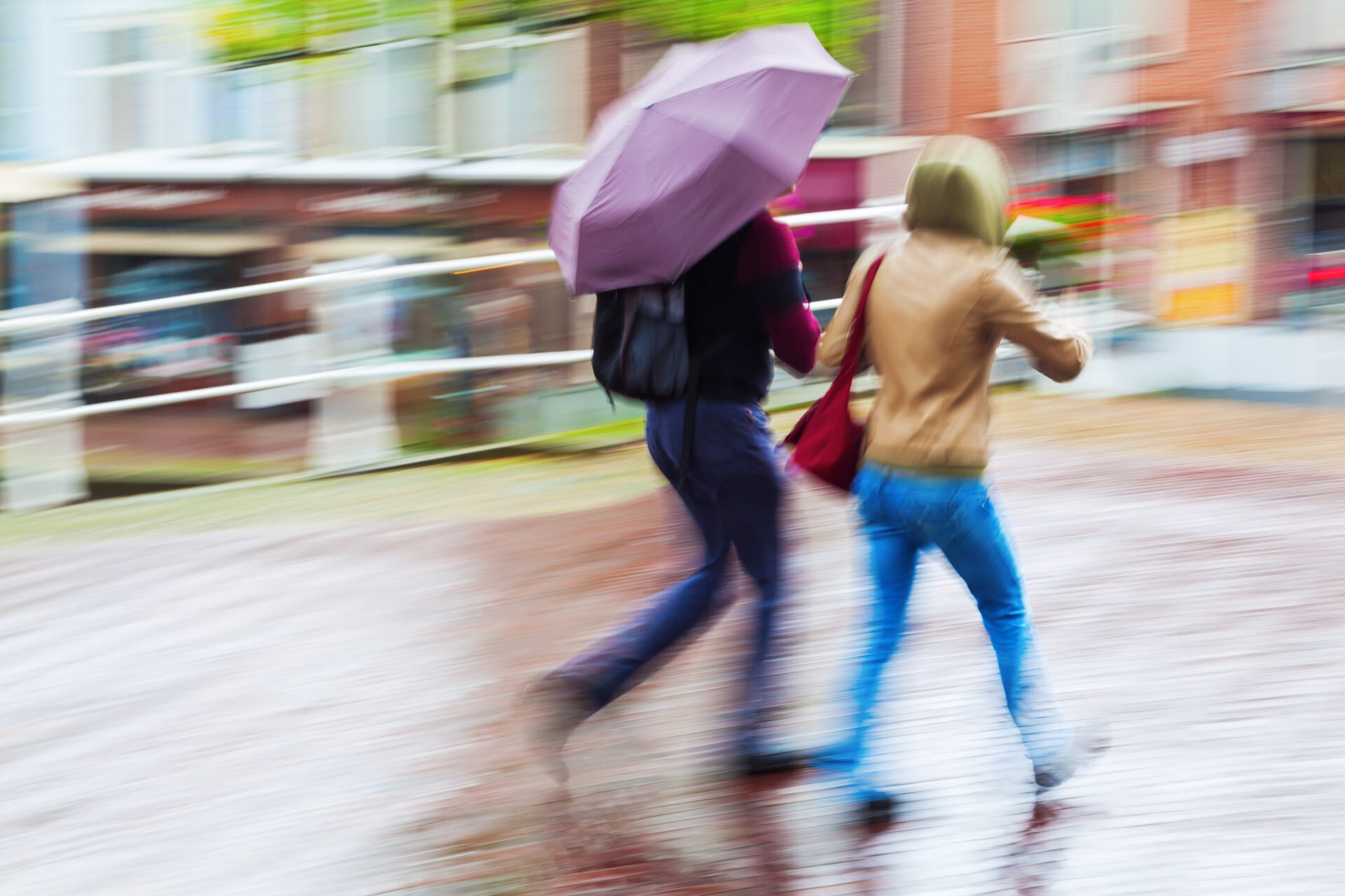 couple running through the streets while it's raining in PFAS free jackets