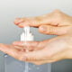 Female hands using hand sanitizer gel pump dispenser