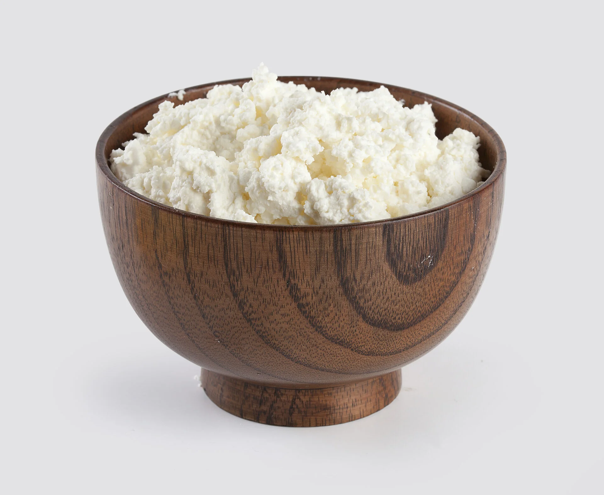 Isolated cottage cheese in the wooden bowl