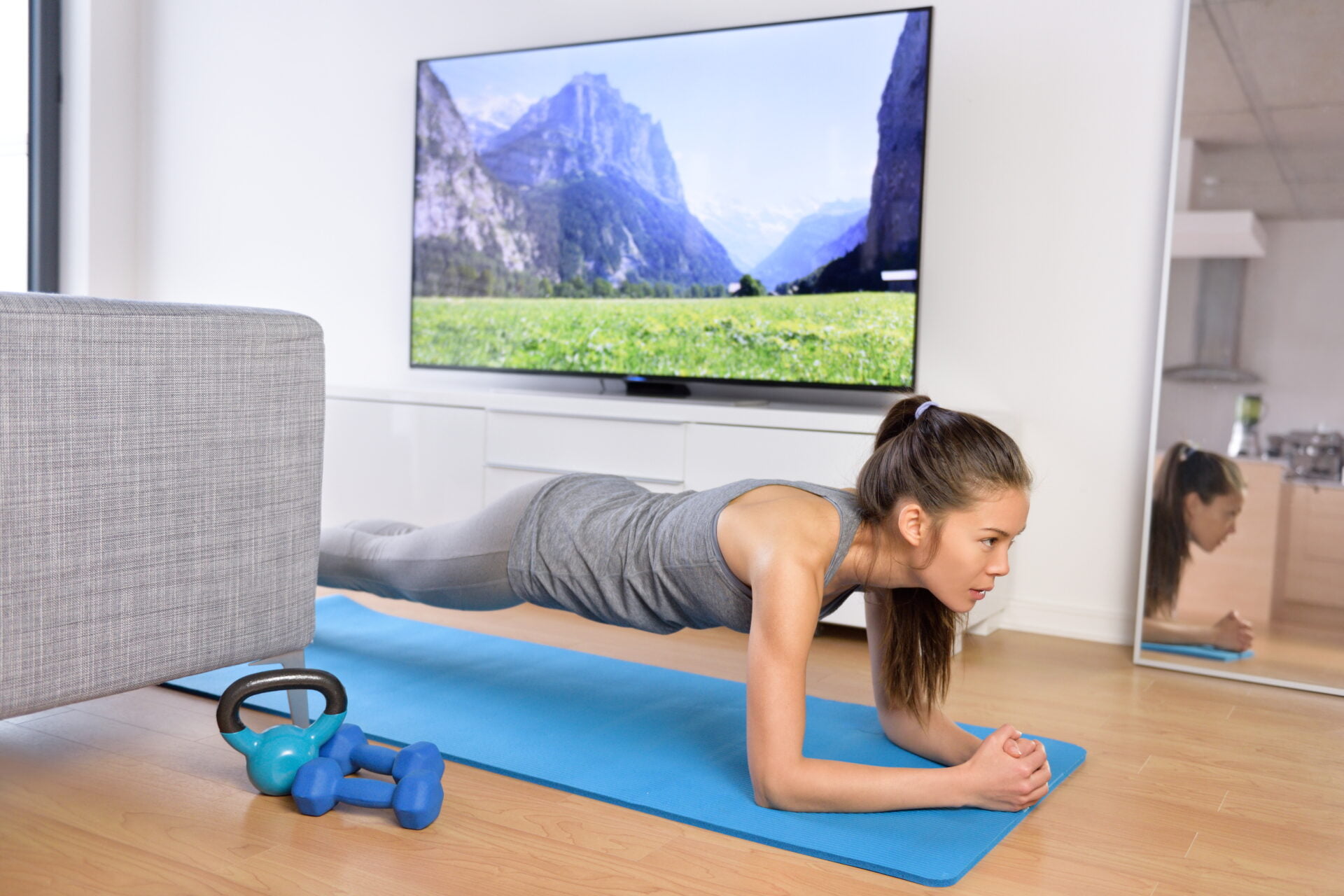 Living room fitness workout - girl doing plank exercises to exercise core at home. Young Asian woman training muscles in front of the TV as part of a healthy lifestyle without going to the gym