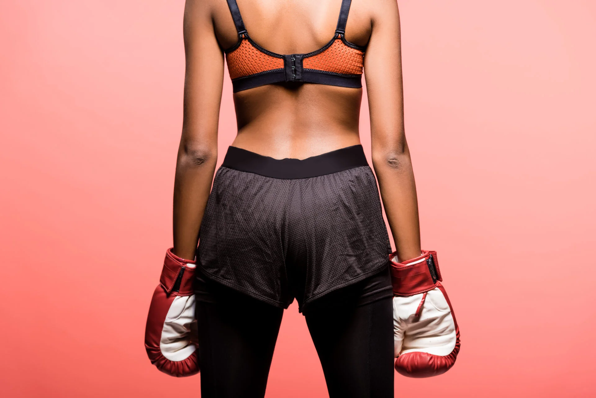 woman wearing sports bras and boxing shorts with boxing gloves