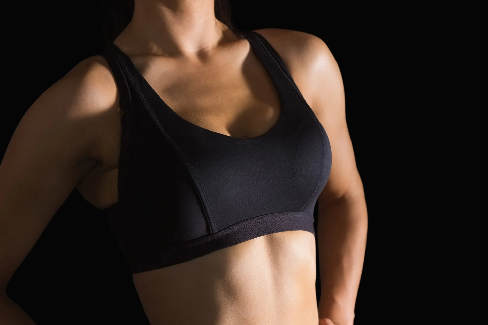 Mid section of slender woman wearing sports bra 