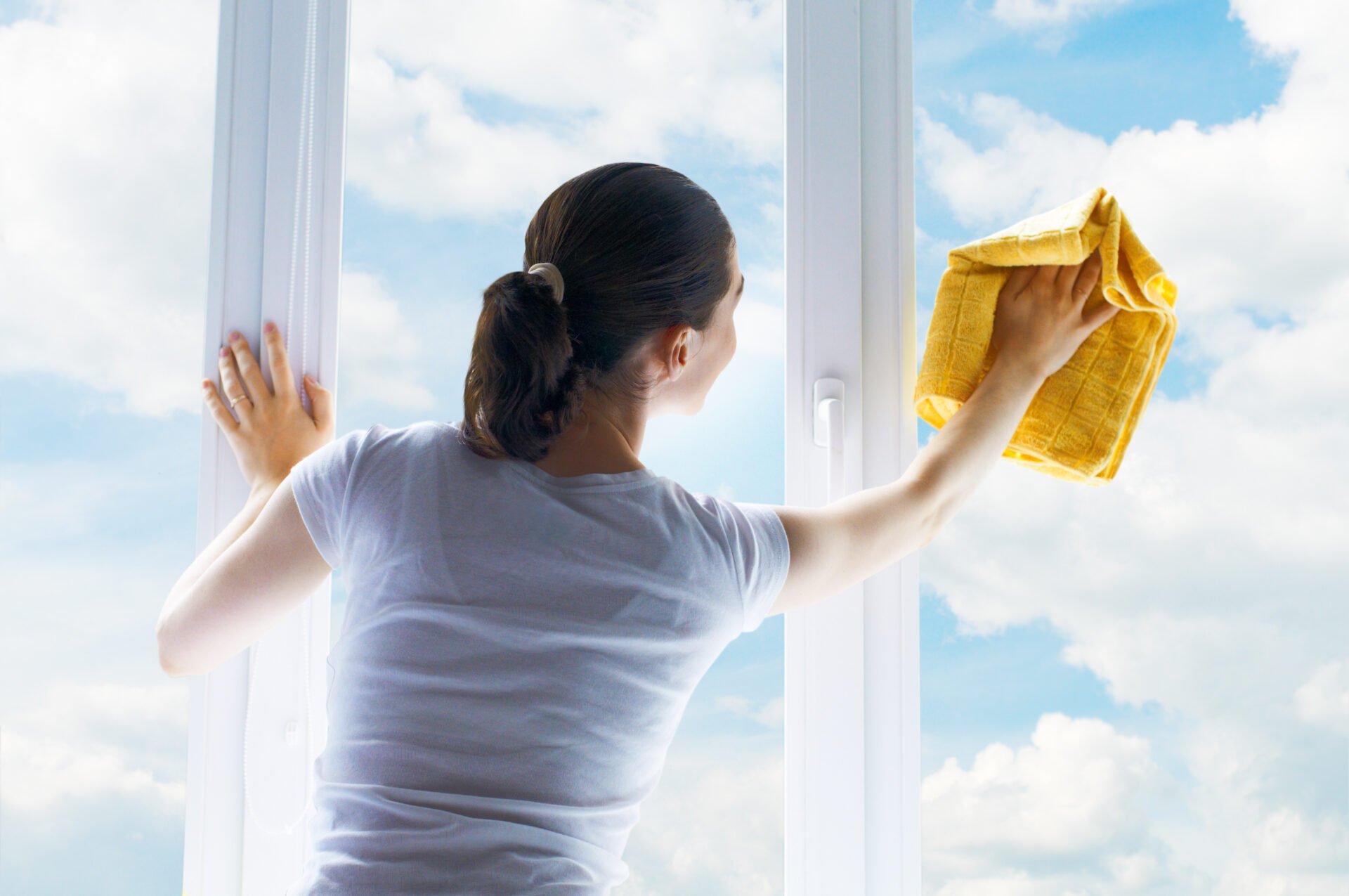 Young woman washing windows with non-toxic window & glass cleaner