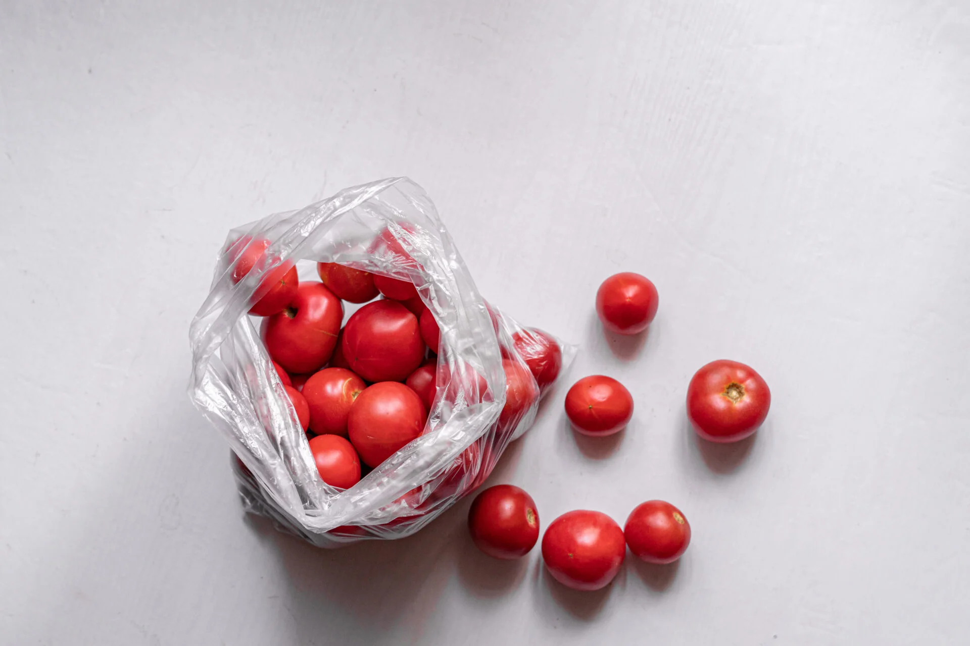 a top view of many red tomatoes in the plastic package begs, the plastic issue