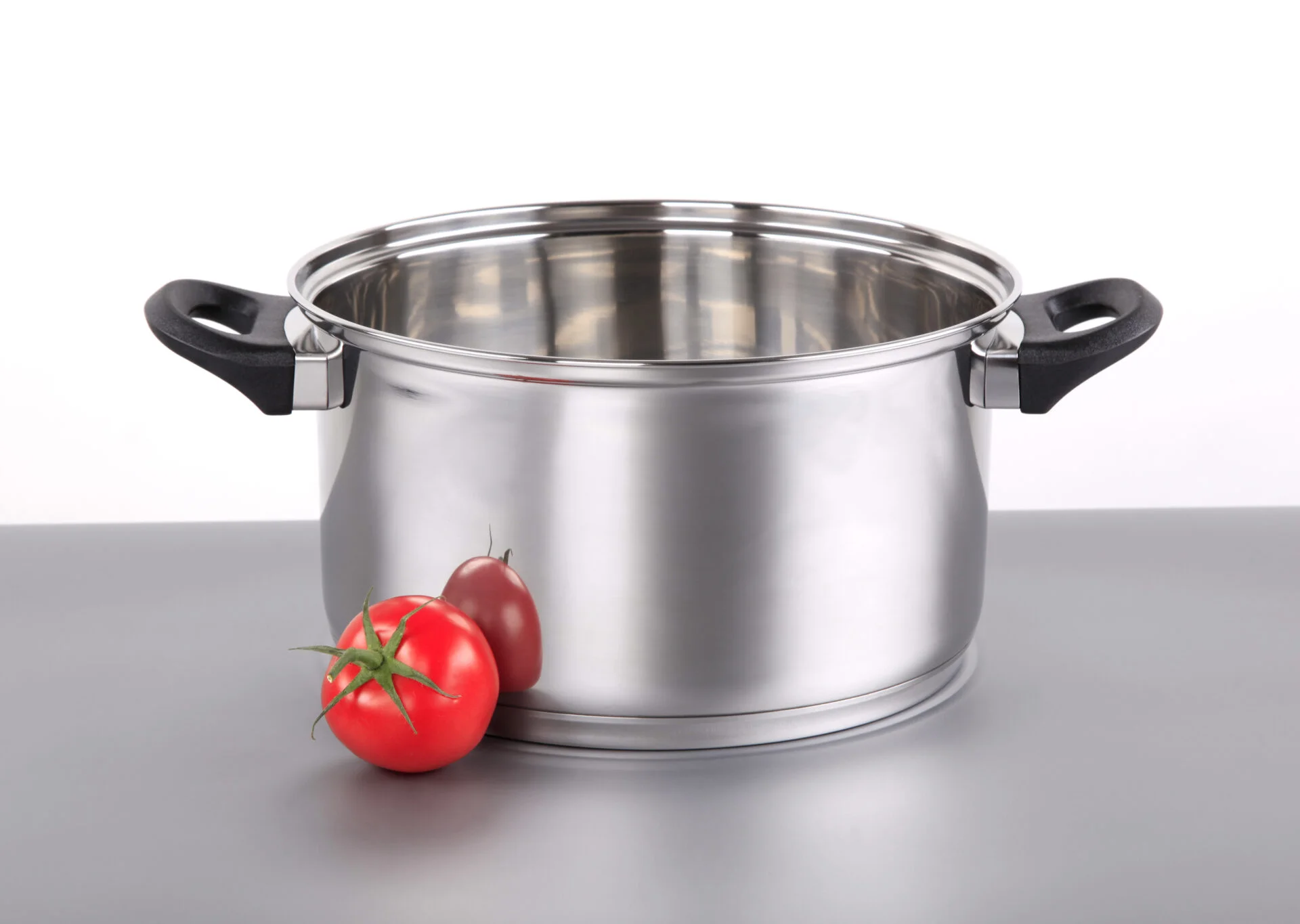 Shiny stainless steel pot and a tomato