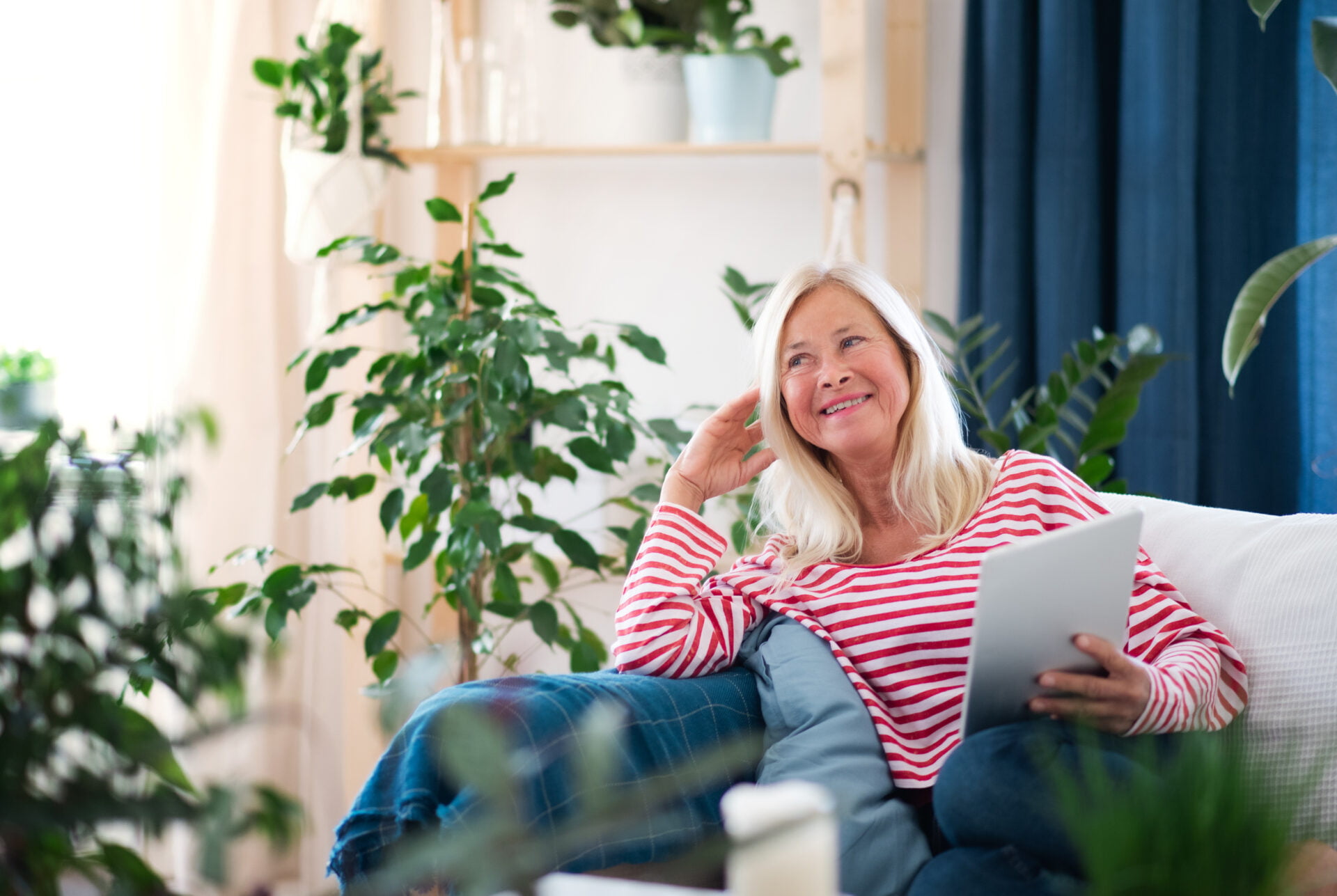 Woman sitting on couch surrounded by plants and clean indoor air