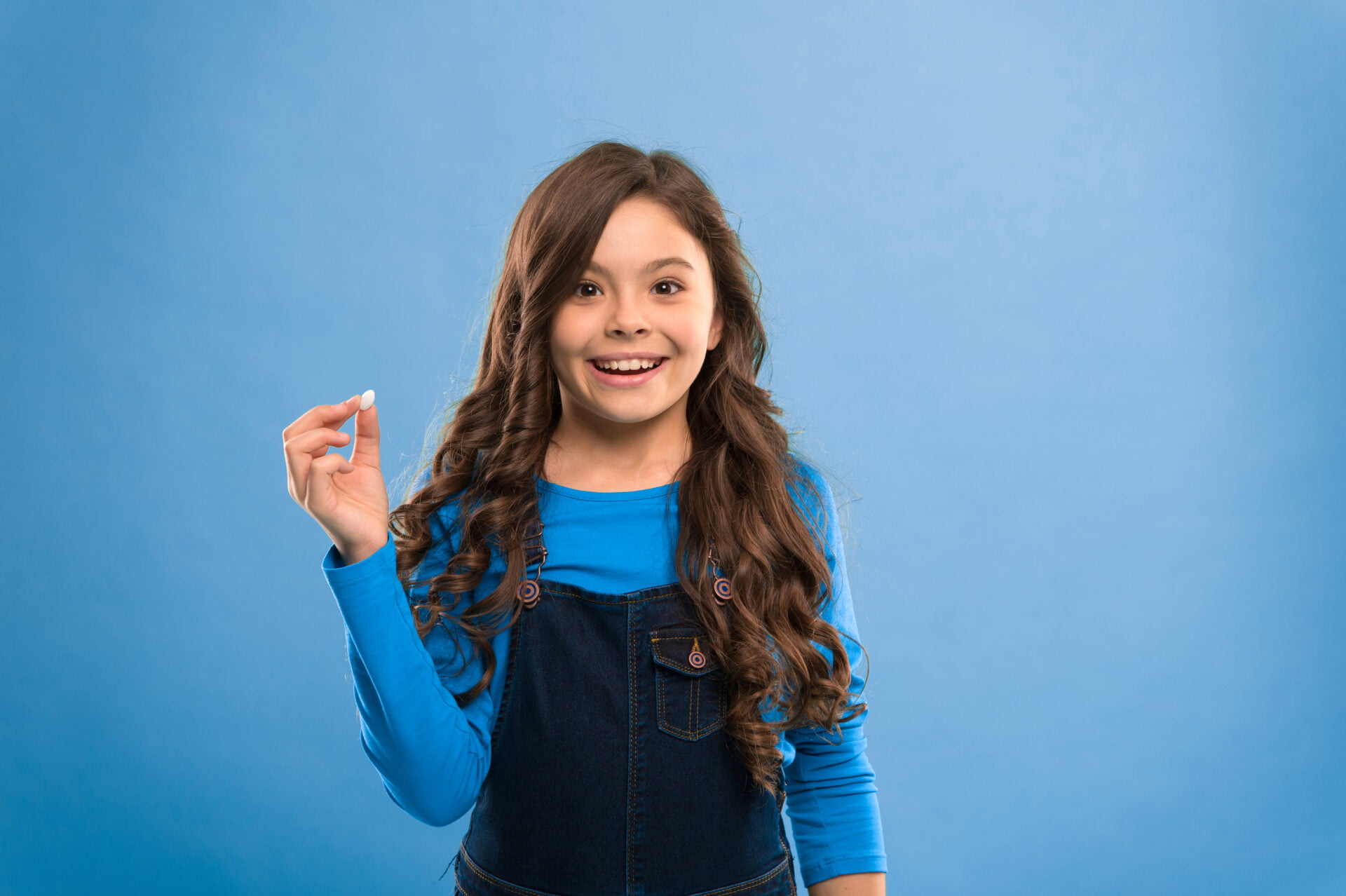 Little girl holding up a probiotic pill
