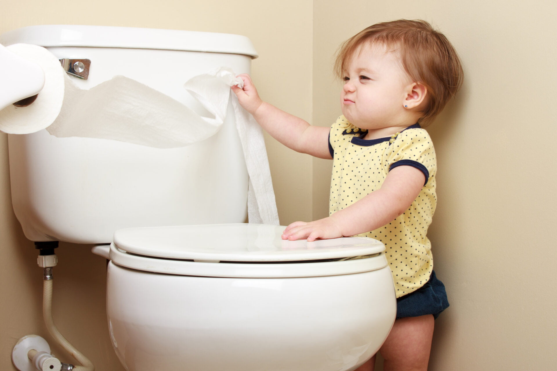 Baby putting toilet paper down the bowl