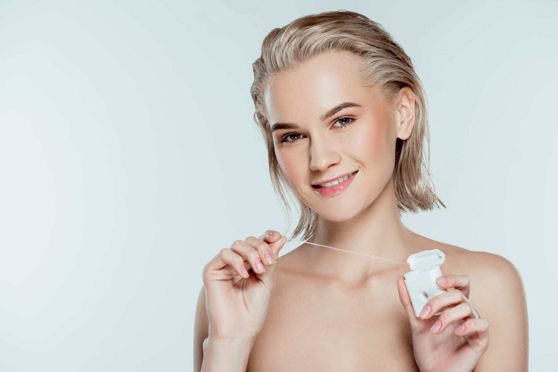 woman with silvery hair holding tooth floss