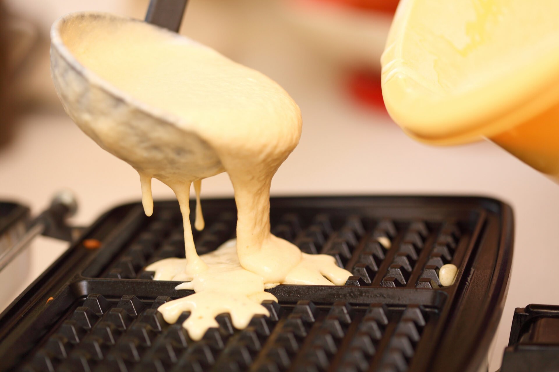 Waffle iron in the kitchen. Preparing homemade waffles, pouring a dough