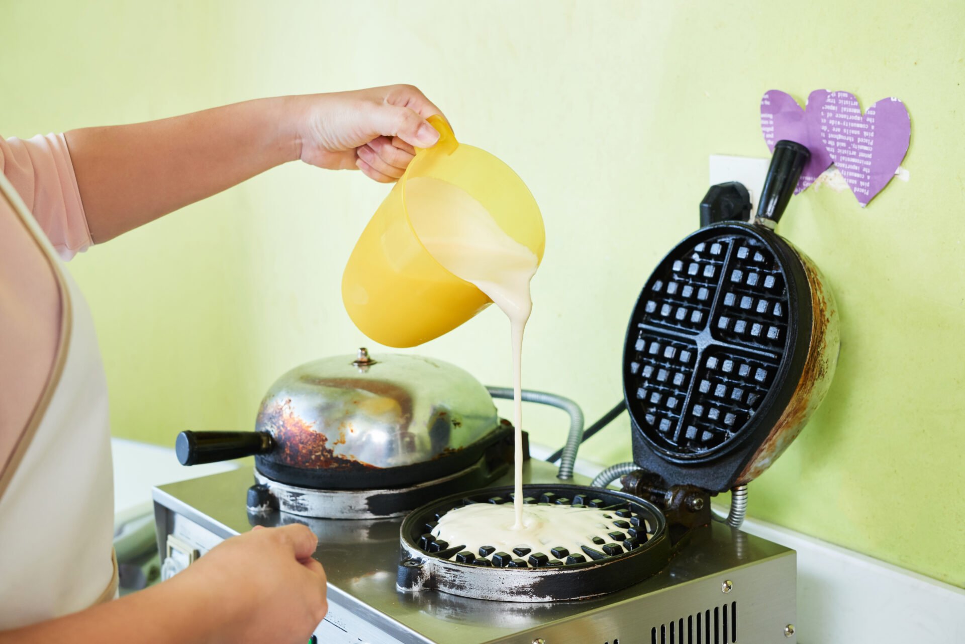 Cropped image of woman pouring dough into waffle maker