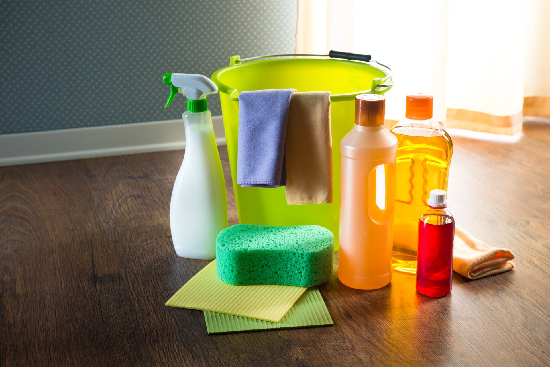Wood cleaners and detergents on floor with bucket, gloves, cloth and sponges