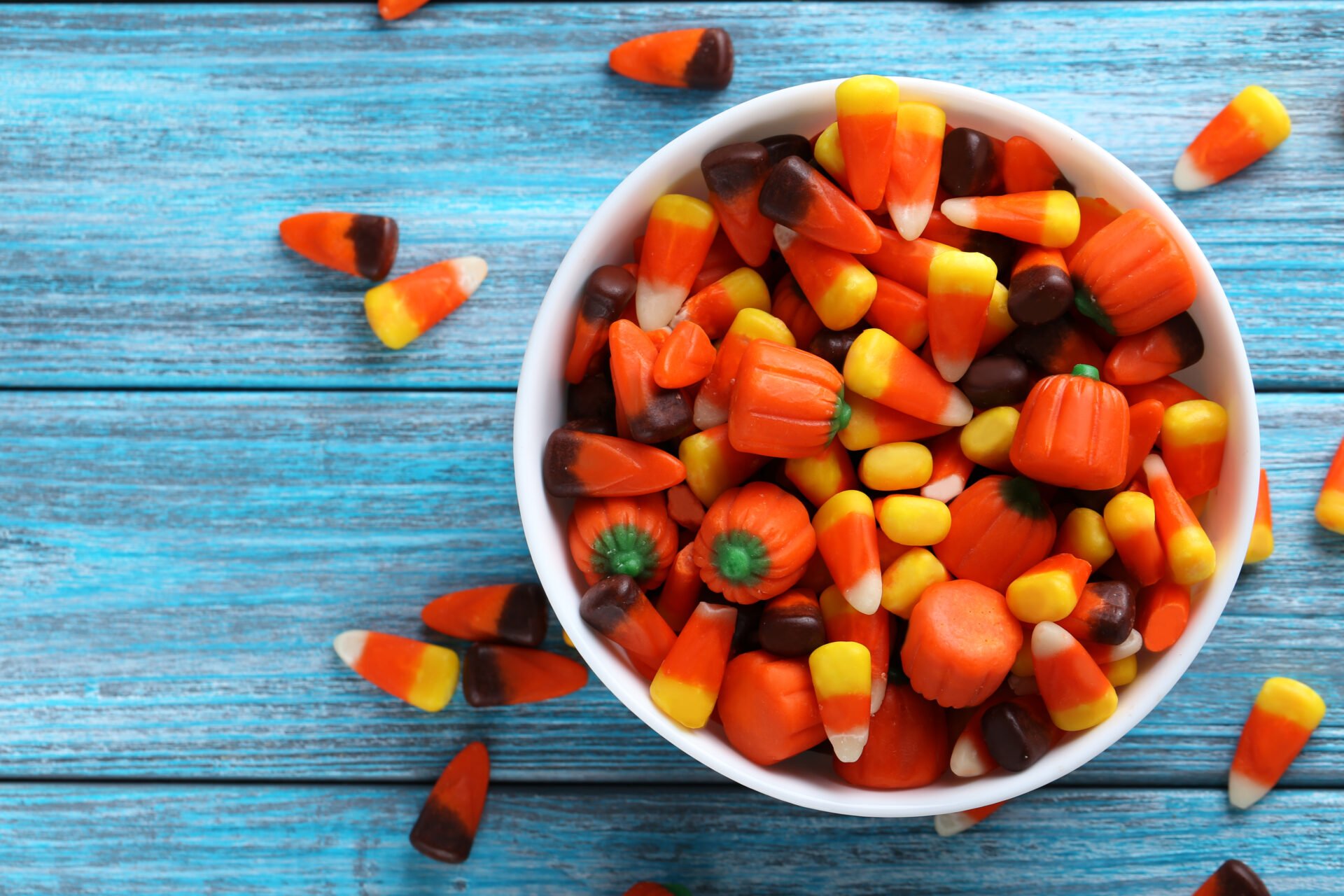 Halloween candy corns in bowl on blue wooden background