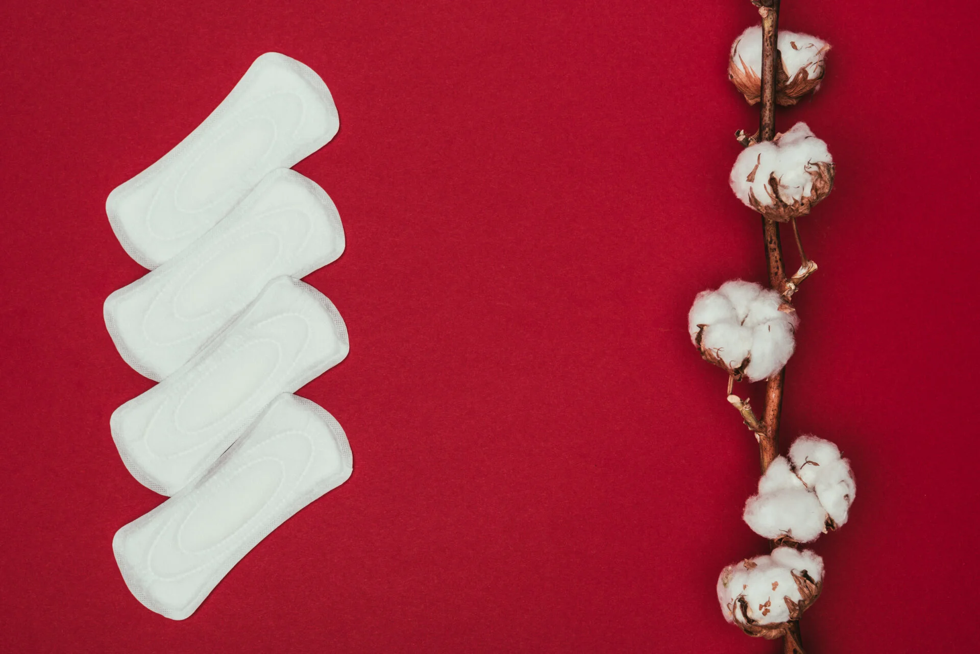 Sanitary pads in front of cotton with red background