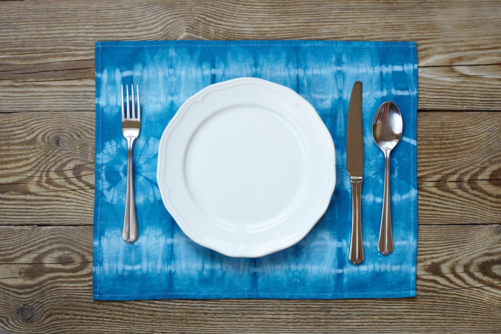 Empty plate on wooden tabletop with tablecloth close up