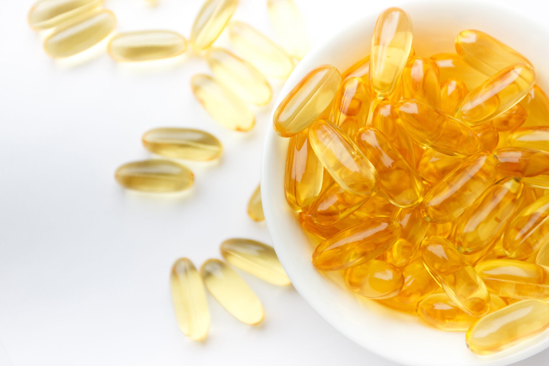 Dietary supplementation. Capsules of fish oil in the white bowl on the light background