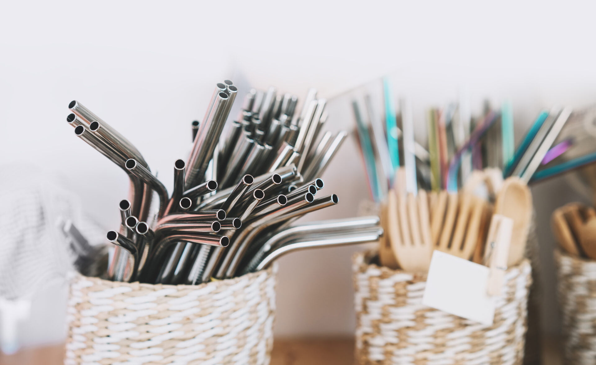 Metallic stainless steel reusable straws on background with other goods in plastic free grocery store. Details of product assortment in zero waste shop. Alternative shopping at local small businesses