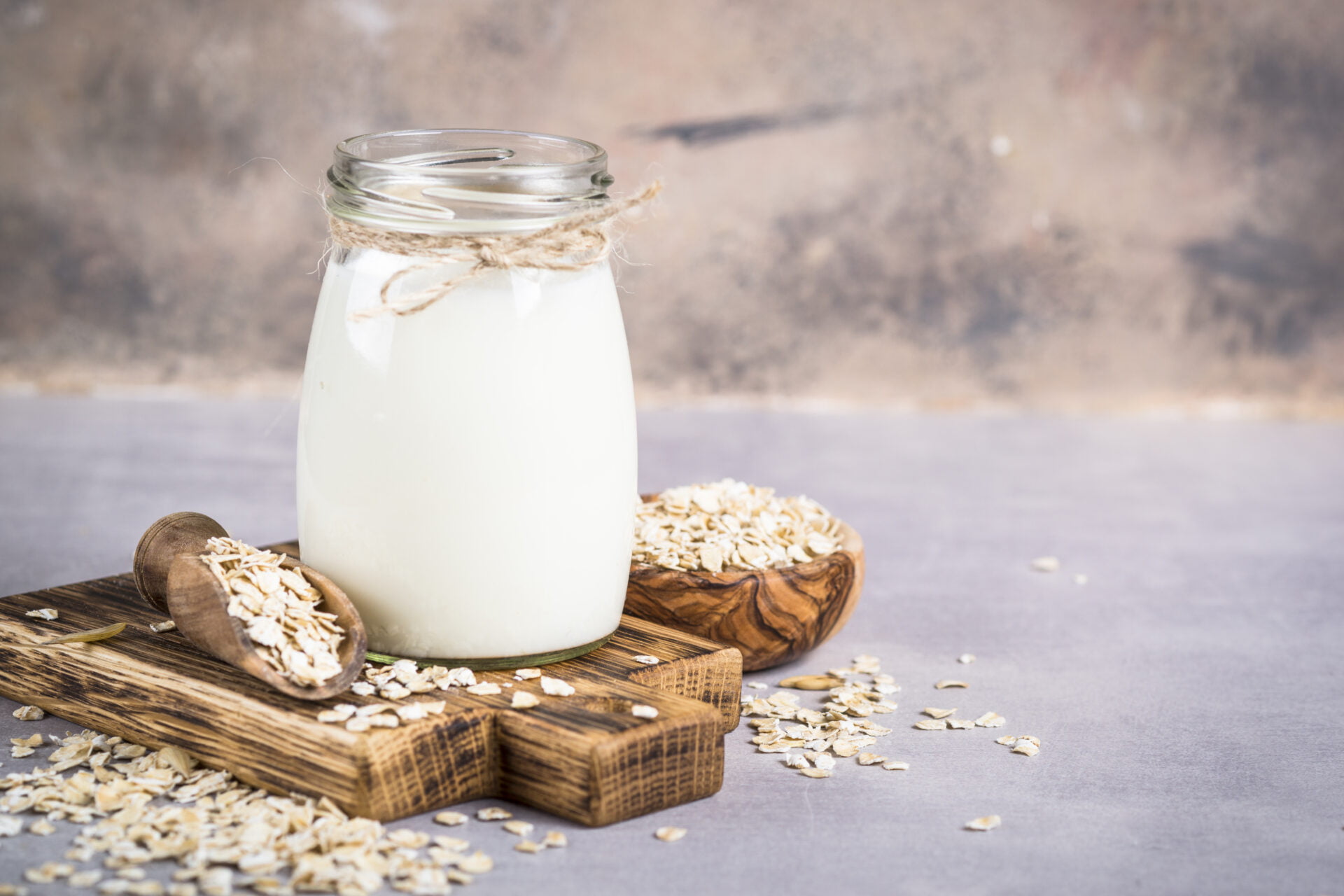 Vegan non dairy alternative milk. Oat flakes milk on stone table