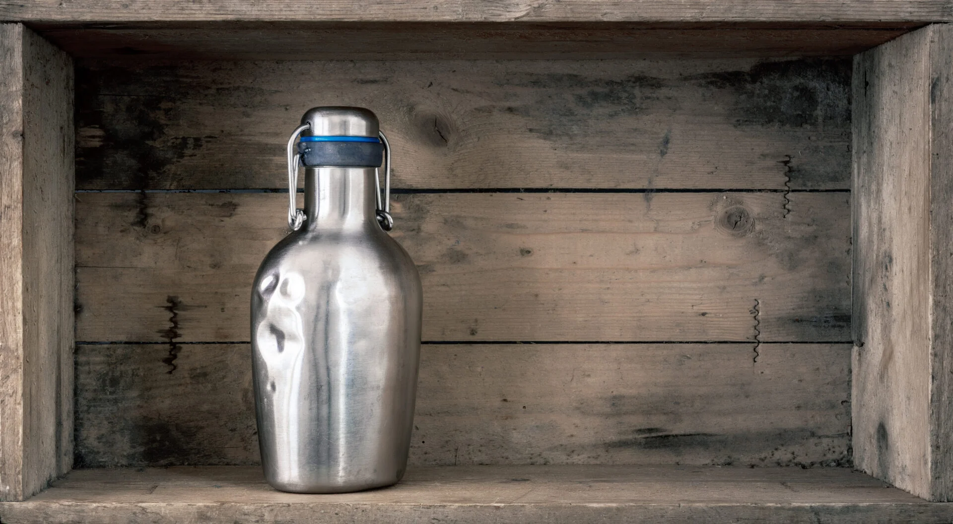 An image of an old dented metal bottle on wooden background
