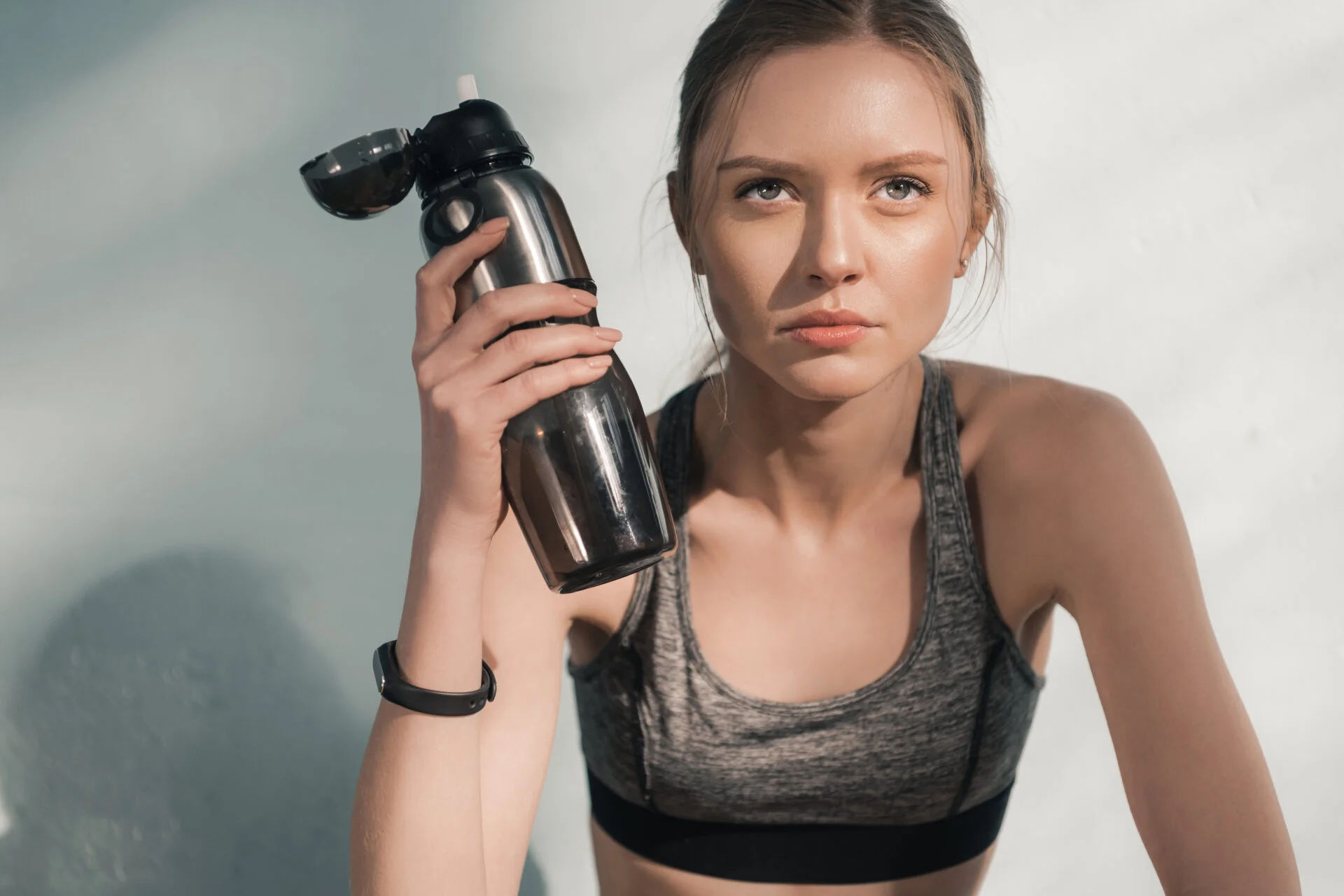 Reusable stainless steel water bottle with a spout held by sporty female 