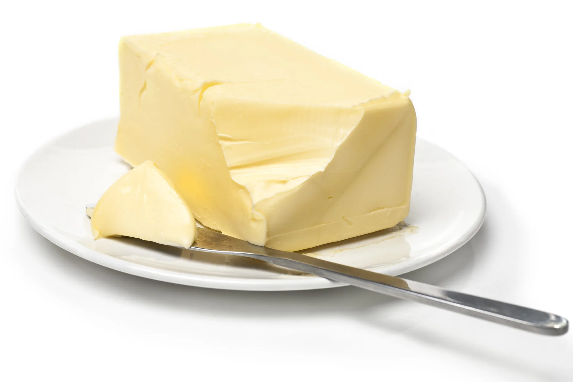 Piece of butter on white plate with knife. White background and shallow focus.