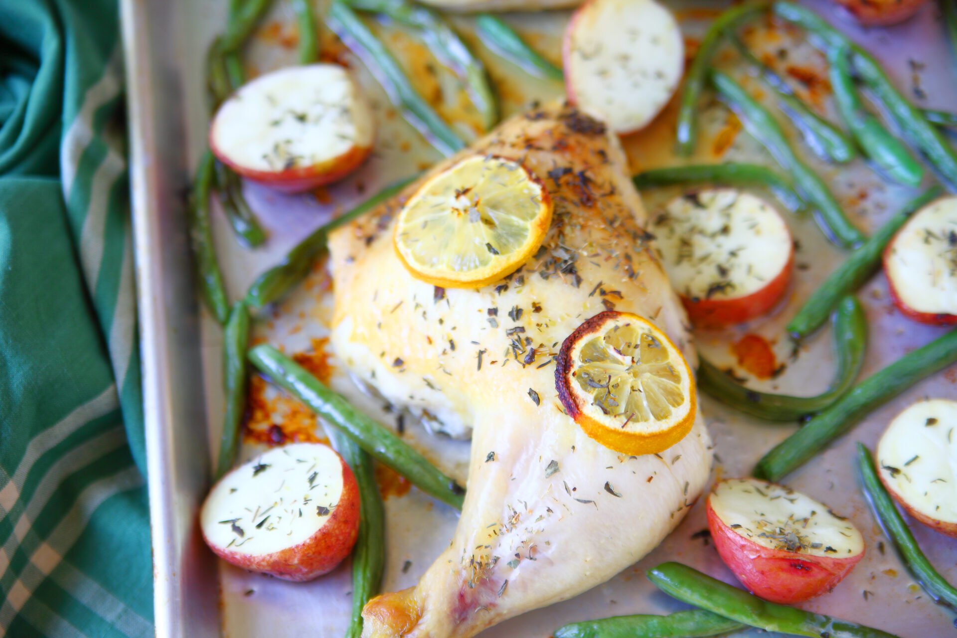 Sheet pan meal of chicken, potatoes and green beans with lemon slices