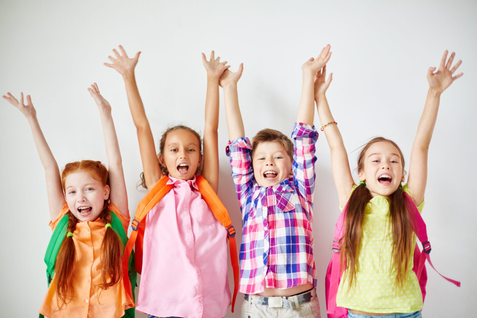 Ecstatic kids with backpacks raising their arms