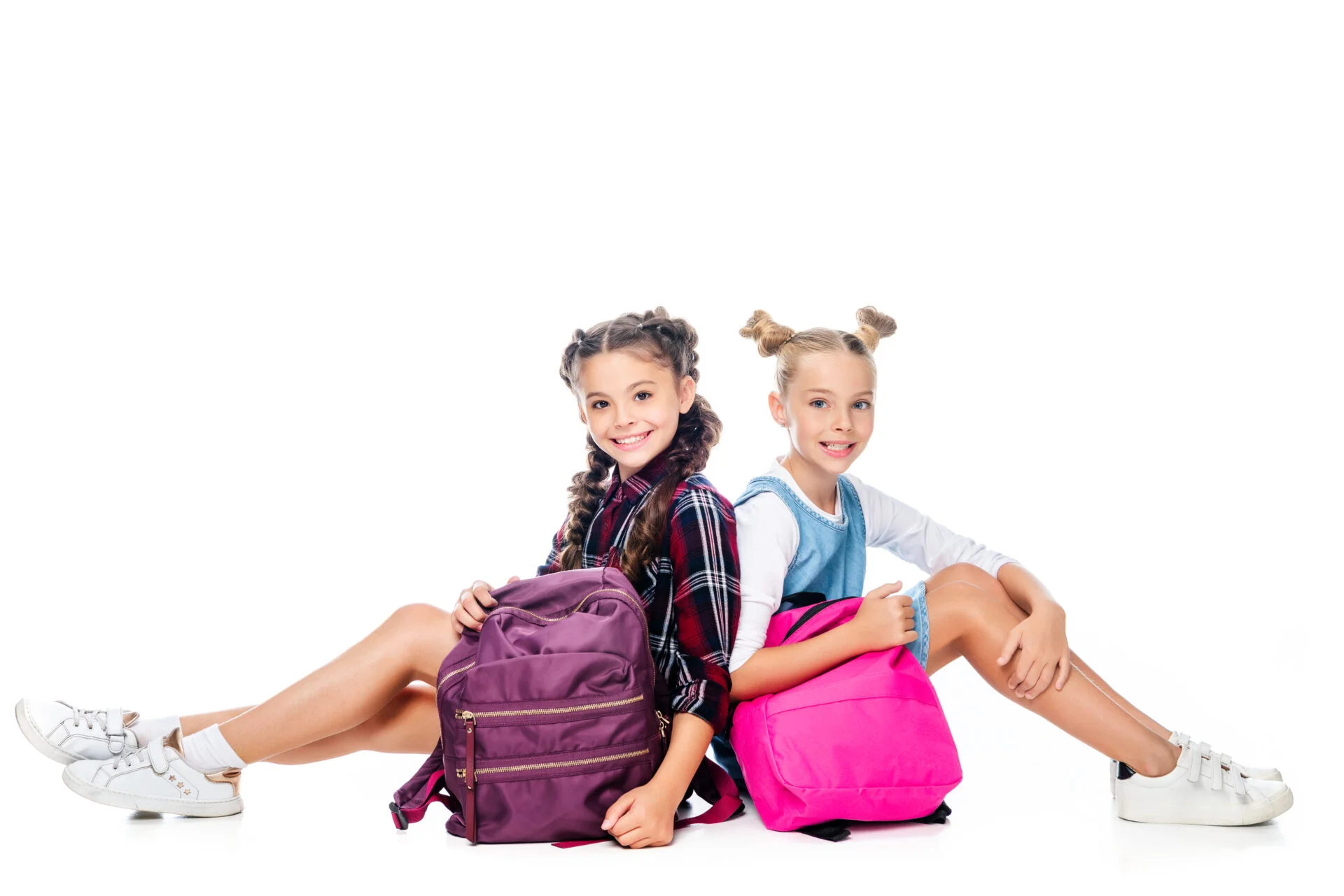 Two girls sitting on the ground holding their PFAS free backpacks