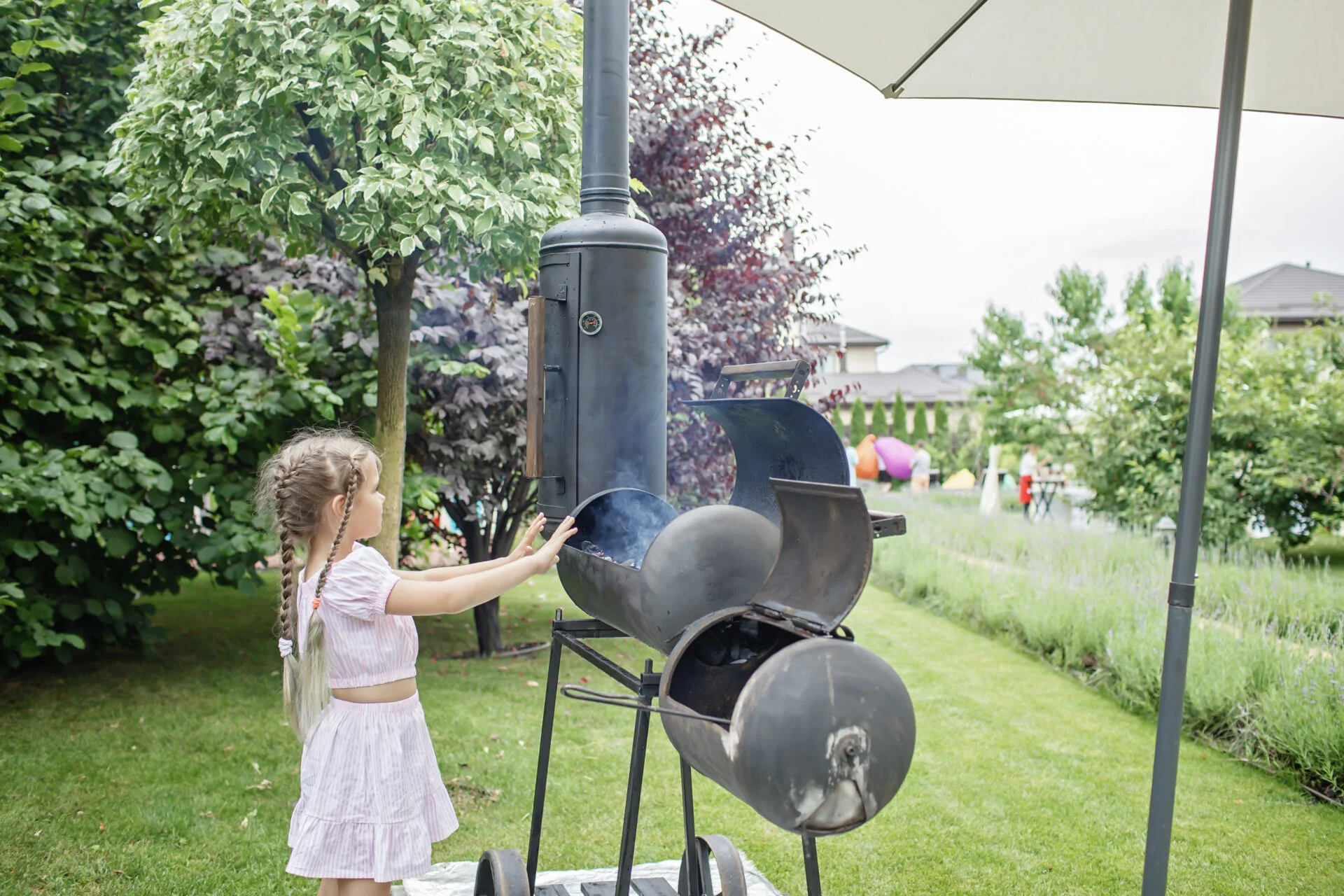 Smoker grill in home backyard, container with coal, smoke coming out of a smokestack, barbecue on green background, family patio, outdoor bbq party on open air