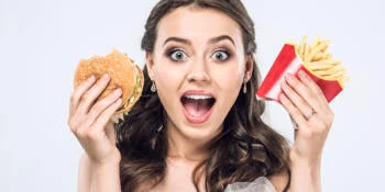 Woman holds up fast food with PFAS inside the packaging that she is about to eat