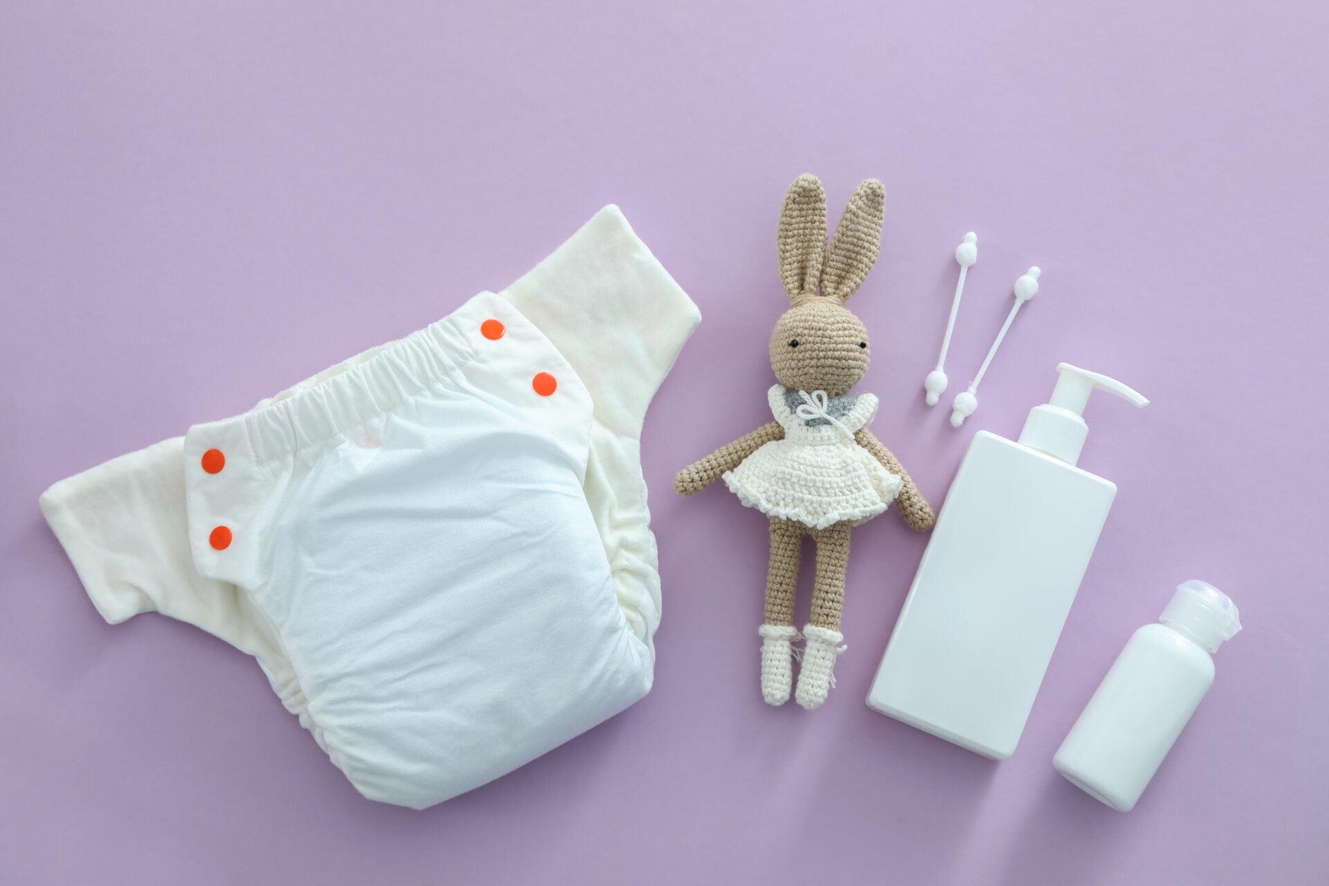 Concept of baby clothes with reusable diapers on purple background