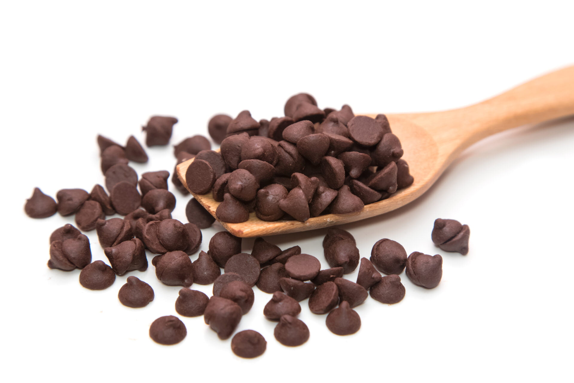 Chocolate chips with low levels of lead and cadmium on a wooden spoon on white background
